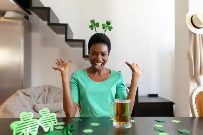 Excited african american woman shouting while looking at beer mug on table. unaltered, people, emotions, lifestyle and st patrick's day celebration concept.