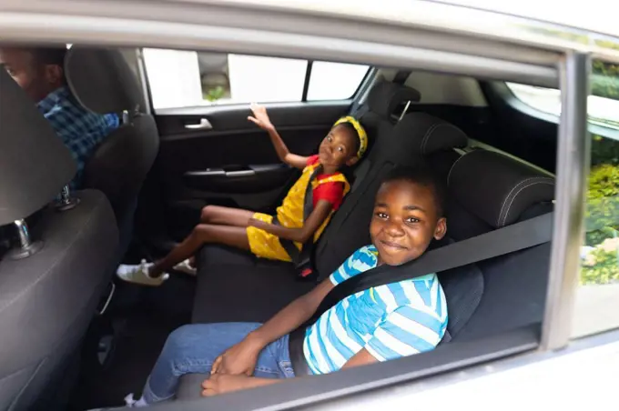 Portrait of smiling african american brother and sister with seat belts traveling in car. unaltered, family, childhood, safety, weekend and travel concept.