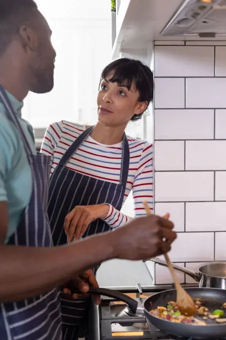 Multiracial young couple cooking food together at home. unaltered, lifestyle, togetherness, preparing food, love, domestic life, food.