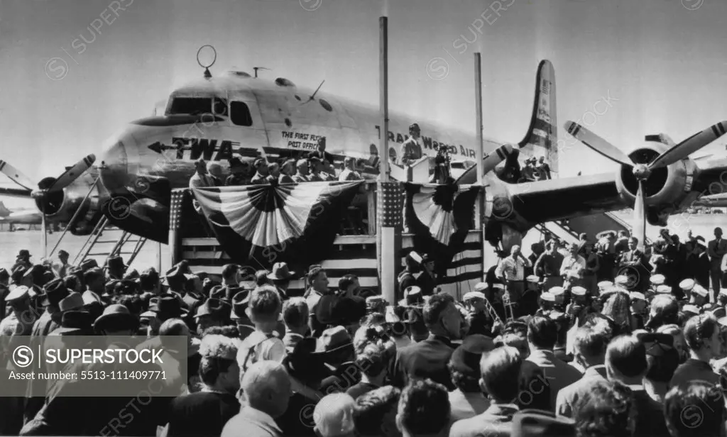 Hannegan Dedicates First Flying Post office - Postmaster General Robert E. Hannegan (speaking on platform, center) dedicates the nation's first flying post-office, a C-54 equipped to sort mail en route, during ceremony at national airport here today. The ship will make stops at Dayton, Chicago, Pittsburgh and New York on its initial flight, starting today. September 25, 1946. (Photo by AP Wirephoto).