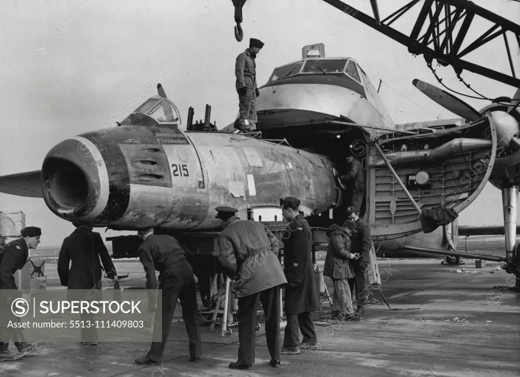 Bristol Freighter As Air Ambulance -- A damaged Sabre Jet (F-86 Sabre Jet) being placed inside the Bristol Freighter at Gros Tenquin, for its journey to England, to be repaired. Much in the same manner as a king-size reptile swallowing his food intact, this RCAF Bristol Freighter devours an F-86 Sabre jet at Gros Tenquin, near Metz in north east France, where the RCAF'S No. 2 Fighter Wing is stationed. As the comparatively little Sabre fuselage goes "down the hatch", supervising officers check i