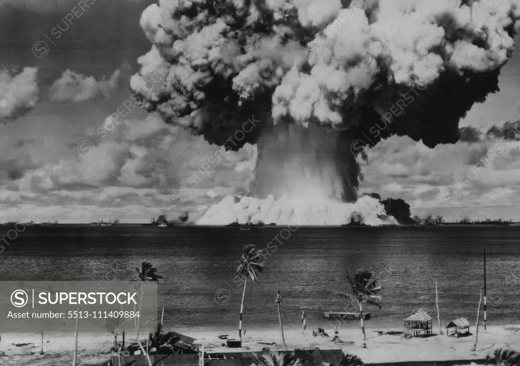 Second Bikini Blast As Viewed From Shore -- A column of water some 2,000 feet across at its base and 5,000 feet high boils up out of Bikini lagoon amid anchored ships as the underwater atomic explosion is set off on July 25. Bikini atoll shoreline in foreground. August 3, 1946. (Photo by AP Wirephoto).