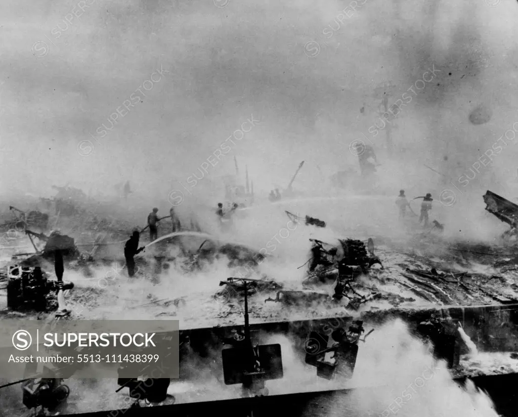 Crew of the bunker hill fights courageously to bring flaming gasoline on her flight deck under control. Charred wreckage of planes which were awaiting take-off at the time of the attacks attests to the destruction the stricken carrier suffered. June 21, 1945. (Photo by ACME).