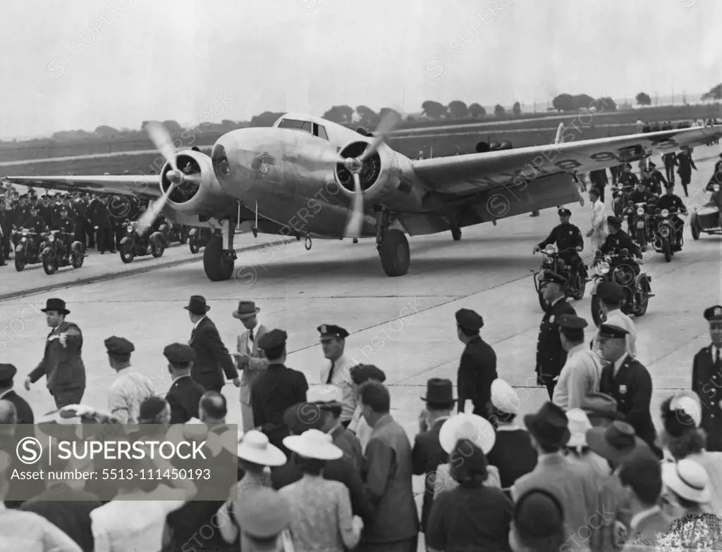 Hughes Completes The Globe Circle -- Here's the world-girdling silver Monoplane of the Howard Hughes round-the-world flight as it taxied into Floyd Bennett Airport, New York City, July 14. A throng of excited New Yorkers were on hand to greet the five inspired airmen aboard. July 14, 1938. (Photo by Associated Press Photo).