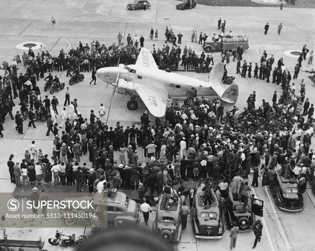 Ring Around An Airsteed -- Howard Hughes twin-motored Monoplane is shown on the concrete apron at Floyd Bennett Airport, July 14, at the end of the flight around the world. Moviemakers Newsmen and officials comprise the crowd. July 14, 1938. (Photo by Associated Press Photo).