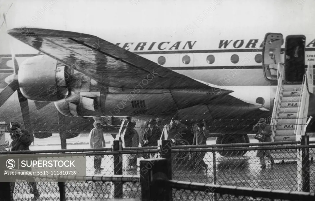 Passengers from A RAA Stratocruiser running thru the rain to the Customs shed at Mascot this afternoon. The plane had just arrived from the US. November 07, 1955. (Photo by Leyden).