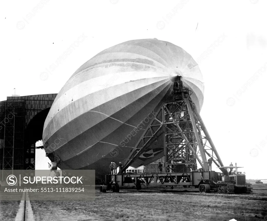 Testing Navy's New Portable Mooring Mast The U.S.S. Los Angeles, hooked to the new portable mooring mast, leaves the hangar here as the mast is drawn gut upon the field by a tractor preparatory to testing the new facilities which the new apparatus offers for landing as well as launching. The portable mast passed the test satisfactorily and is said to mark a real development in hangar equipment since it greatly decreases the number of men required to assist in the "take-off." May 26, 1930. (Photo