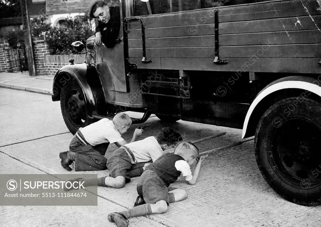 Scenes From "Doodle-bug" Alley, Southern England - The kids doing "Commando" staff in "Doodle-Bug" Alley watched by the lorry driver. September 17, 1944. (Photo by L.N.A).;Scenes From "Doodle-bug" Alley, Southern England - The kids doing "Commando" staff in "Doodle-Bug" Alley watched by the lorry driver.