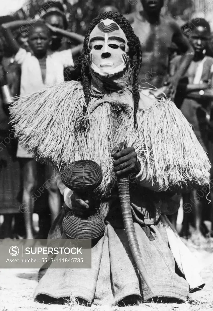 Congo Folklore -- One of the some twenty characters in the Mbuya dance of the Bapende tribe... An African Folklore 'play'. He wears a white-painted mask, Pigtails, and carries a basket filled with dried seeds and an Antelope horn. The Folklore of Africa lies, not in books, but in the Rhythmic Tribal dances that are handed down from generation to generation. the origins of the dance steps, the gestures and the sometimes fearful looking costumes are deep in the past, and deal with drought and rain