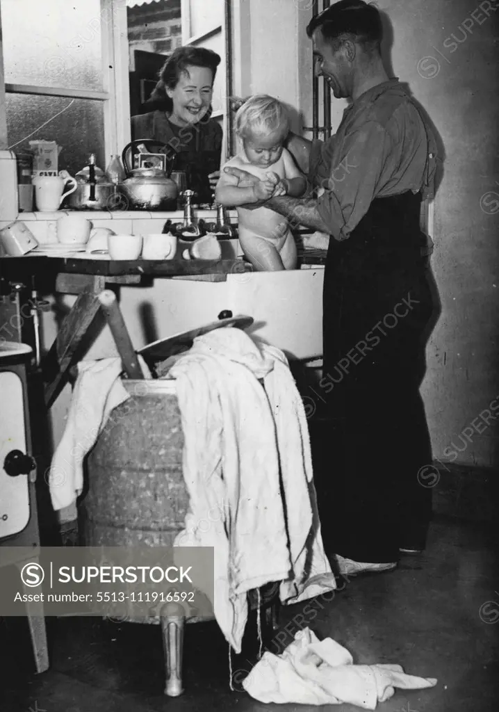 Husband Becomes Housewife For A Week -- Mrs. Joan Ashford came home from work and peeped through scullery window of her home at Dudley-road, Bedfont, Middlesex.There was her husband - surrounded by crockery washing and irons - struggling to bath baby Donald, thirteen months , in the sink. Donald was helping by trying to bath Dad, too. Mrs. Ashford chuckled. Well, how do you like housework" she asked. Arthur Ashford wiped his damp forehead. "It's Murder". He assured her, fervently. "I wouldn't h