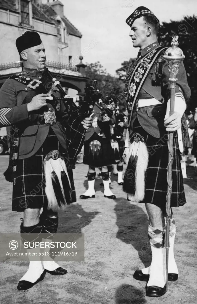 Pipe Band Of King's Guard At Bal Moral -- Those two resident figures are Pipe Major Donald Maclean (left) in charge of the King's Gurad pipe band, at with Drum Ka Jor James Watson (right) who heads the pipe band, he recently won the World's Drum - Major Championship in Edinburgh. They both come from the Highland Brigade Training Center.  The King's Guard that is on duty when the king is in residence at Belmoral is chosen from the six highland Regiments. The personnel is changed each time the ki