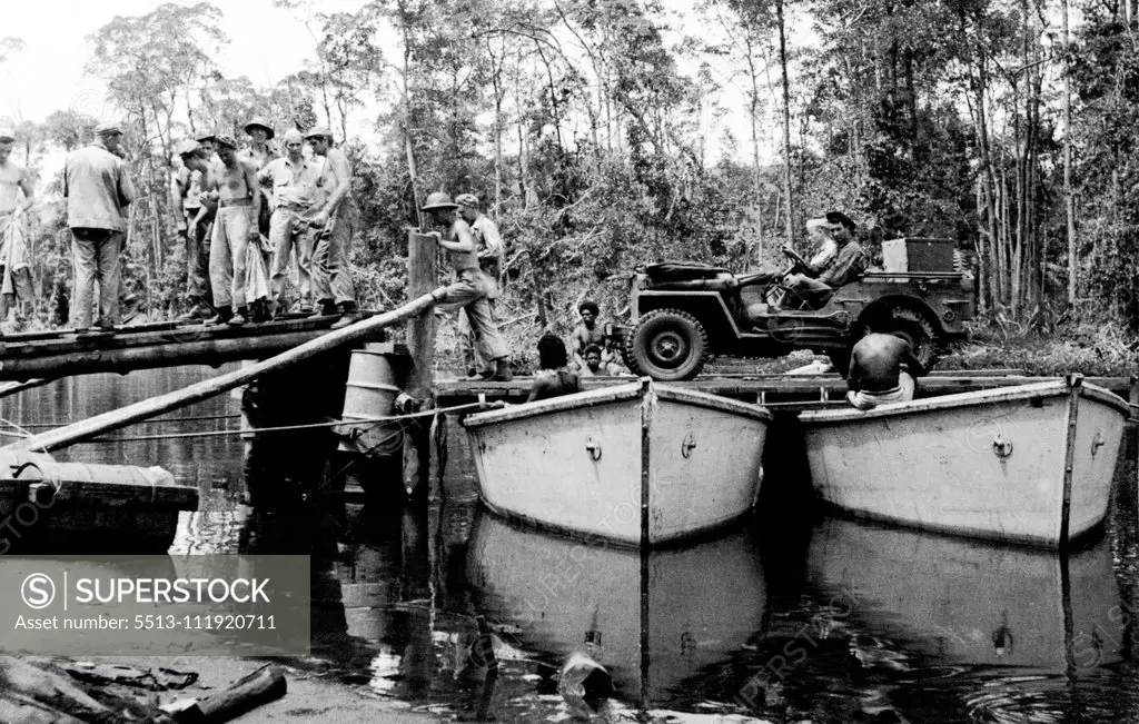 A Jeep goes across the river on a pontoon ferry. Natives haul the ferry backwards and forwards. May 24, 1943. (Photo by Department of Information, Commonwealth of Australia).