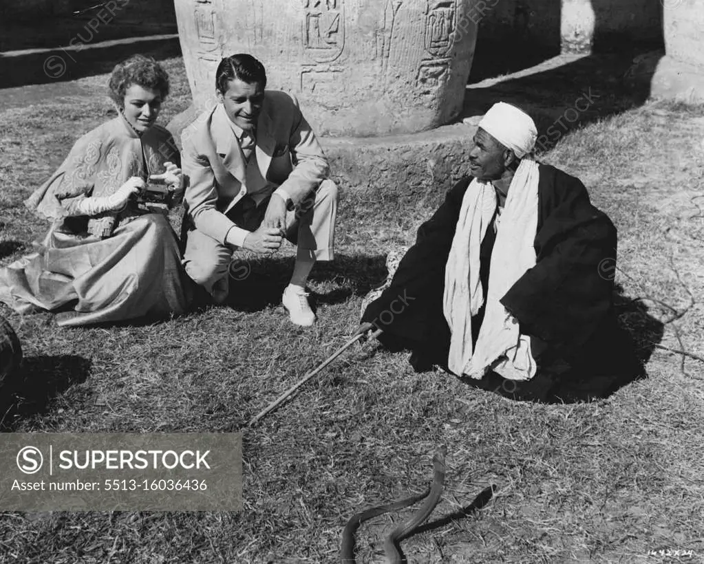 Egyptian Scenes... Between scenes of M-G-M's "Valley of the Kings" in Egypt, Eleanor Parker and Carlos Thompson look on as a local snake charmer in Luxor puts his pet cobra through his daily exercises. Robert Taylor co-stars in the exciting adventure film, most of which was made in Egypt. Robert Pirosh directed. July 3, 1954.