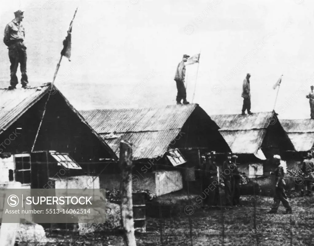 ***** Four communist Pow's stand on top of huts in compound 76 in Koje Island ***** camp to watch and report the activity of the American guards. North Korean flags fly from *****. May 28, 1952.