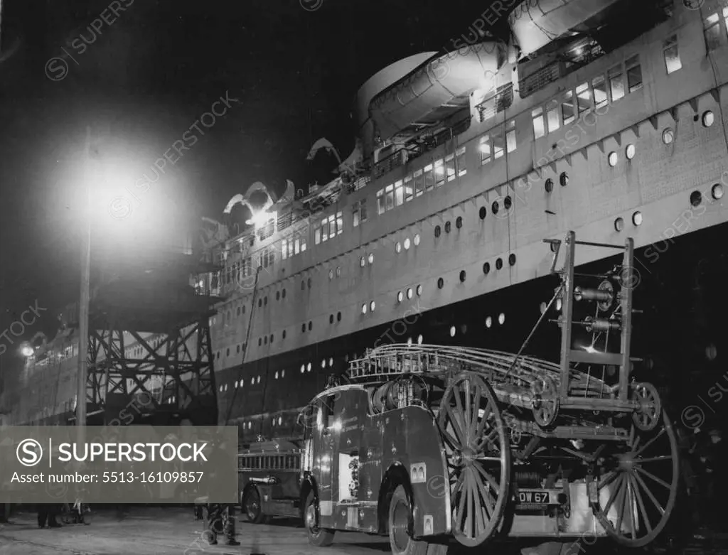 "Queen Elizabeth On Fire In Southampton Dry Dock -- Fire-engines and firemen stand by alongside The Queen Elizabeth in Southampton dry dock here. Fire broke out aboard the Queen Elizabeth, the world's largest ocean liner, in dry dock here to-night. Alert firemen, however, brought the fire under control in under an hour, saving the vessel from possibly a similar fate as that of the Empress of Canada which was destroyed by fire at Liverpool on Sunday night. The 83,000-ton Queen Elizabeth is undergoing her annual overhaul at Southampton. January 28, 1953. 