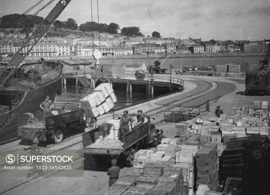 The Relief Of Guernsey And Bark -- Food being unloaded at St. Peters Port Guernsey on the 16th., May 1945. The British Army unloaded all the cargoes. These photographs, taken on May 14th., and 16th, show the people of Guernsey and Sark receiving their first British provisions since 1940. After D-day all German supplied food for the islands ceased too and the Germans at once started to kill off live stock and eat the islander' seed potatoes. Vegetables became more an more scarce, In Guernsey a communal feeding centre was established to which everyone brought whatever they, could soup was made in bathtubs and sold at 7½ d a quart. July 30, 1945.