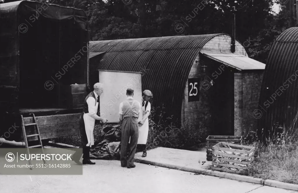 Mr. Cottrell, (seen centre) helps the removal men move his furniture into a Nissen Hut, which he intends to make his home. "Squatters" take over old army huts. Because of the shortage of living accommodation, people, desperate for homes of their own, are moving into disused army camps all over the country. "Squatters" have moved into Vache camp, Chalfont St. Giles, Bucks, which was built for and used by the United States Army. Sanitation is good and the electric light is still working. August 21, 1946. (Photo by Sport & General Press Agency, Limited).