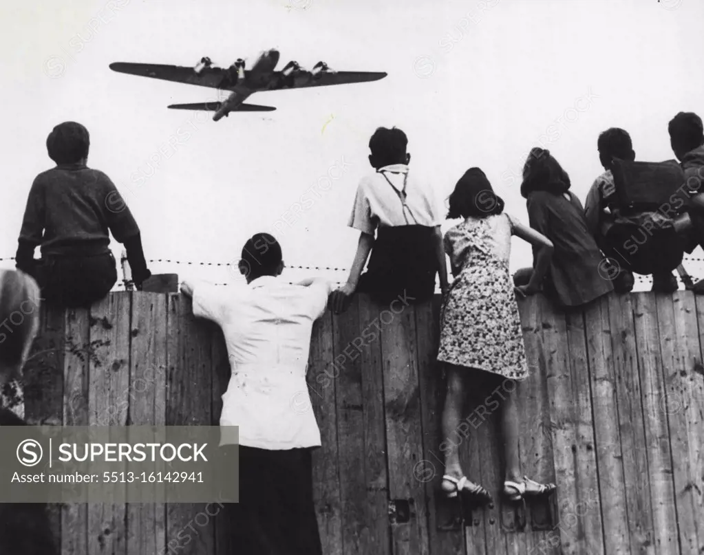 Aircraft Setters At Templehof - Berlin children have a new pastime these days as they gather on the fences around Templehof Airport, Berlin, Germany, watching the fleets of American planes arrive with supplies for the city, now on short rations because of the land and water blockade established by the Russians. An American four- engine transport flies ahead. May 07, 1948. (Photo by AP Photo).