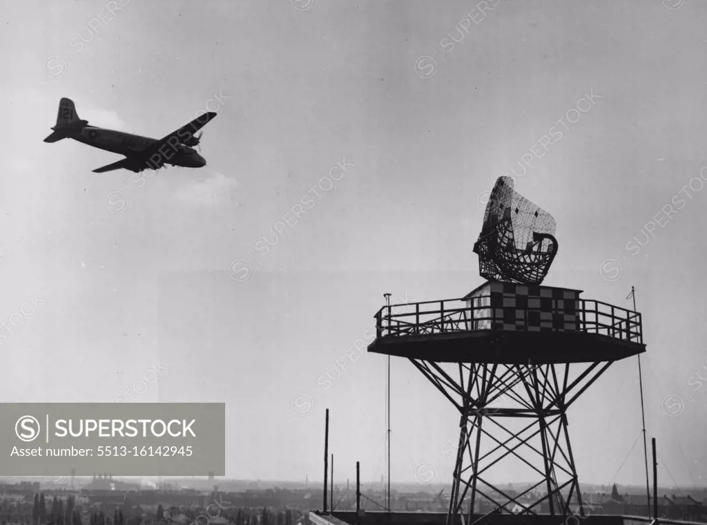 Secret Of The Airlift (First Of Seven) -- A "Vittles" Plane on its return flight to Frankfurt sweeps close by the "Windmill" antenna of the CPS-5. Looking like a against wire marketing basket turned on its side, the antenna whirls round and round. The curved arm (at right) shoots an electronic beam out into space and picks up reflections of that beam as it bounces back from any objects it strikes, in this case, the planes of the airlift. May 06, 1949. (Photo by ACME Newspictures).