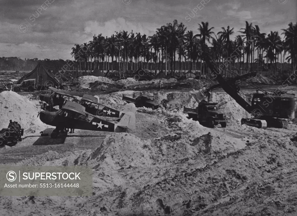 U.S. Forces Rebuild Captured Japanese Airfield - U.S. Army Piper Cub planes, used for observation flights, take cover behind an embankment thrown up for their protection while Seabees, members of the U.S. Navy's construction battalions, work with heavy equipment to rebuild an airfield captured from the Japanese in the Admiralty Islands of the Southwest Pacific. Seizing control of vital areas in the island chain, American forces severed Japanese supply lines to enemy garrisons on New Britain and on the Northern Solomon Island. April 17, 1944.