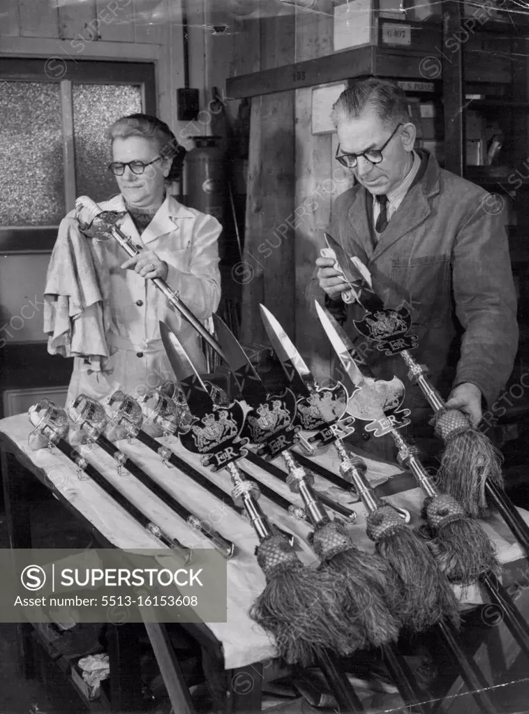 Coronation Weapons Given Their Sparkle by Factory Workers. Mrs. May Fry of Acton polishing swords at the factory, while Mr. Herbert McNab of Fulham, London, foreman sword cutter, cleans some partizans sent from St. James's Palace to be renovated with the new Royal cipher of Queen Elizabeth II. Partizan of this type are carried by the Yeoman of the Guard, Tudor-uniformed Royal bodyguard. A team of craftsmen, and women in a factory at Acton, Middlesex, are now hard at work making 2,000 fine swords for the Coronation. January 24, 1953. (Photo by Reuterphoto).