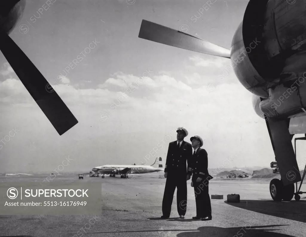 Out on the tarmac, Willcox and Captain E. Robertson (left) survey their aircraft before they take off on a flight overseas. April 20, 1955.