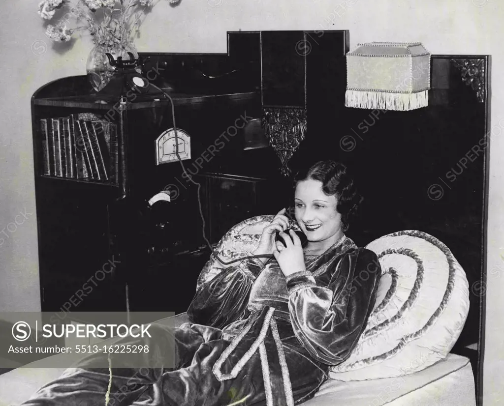 Beauty At Radiolympia -- Radio, Bookcase, Clock and Telephone, Miss Angela Ward, "Miss England" of 1933, demonstrating a compact ***** model by the City Accumulator Company, which will be seen at Radiolympia next week. September 24, 1934.