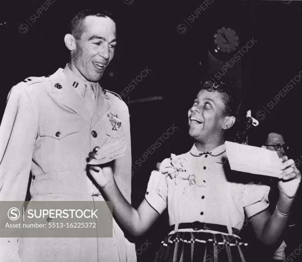 Gloria Shows Her $16,000 To Contender For $32,000 -- Gloria Lockerman, the 12-year-old Baltimore, Md., spelling champion, shows Marine Capt. Richard McCutchen, of Worthington, Ohio, checks for $15,500 for her education trust fund and one for $500 to use as she wishes after she decided not to go on of $32,000 in television quiz show "The $64,000 Question," tonight. Capt. MacCutchen reached $16,000 tonight on a five-part question on breads. He has until next week to decide if he'll do as Gloria or go on for $32,000. August 30, 1955. (Photo by AP Wirephoto).