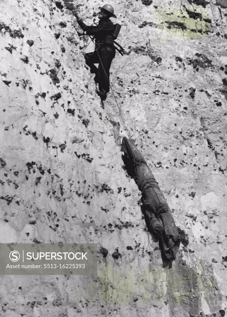 Walkie-Talkie Aids The Rescuers - Dragging the "body" behind him, Sgt. Humphrey, in touch with his collages above over the radio, begins the long ascent, He were a special helmet to protect him from falling rock dislodged by the *****. For many years the Eastbourne police have risked their lives to rescue accident and suicide cases on the 550 ft high, dangerous Beachy Head. Now the elaborate rescue apparatus they have built up has been reinforced by "walkie-talkie" apparatus to make the almost vertical descent less dangerous. April 07, 1949. (Photo by Fox Photo).