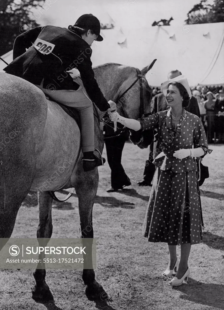 The Queen At Royal Windsor Horse Show -- The Queen presenting a prize, winning rosette to J. Bayes on city lights. The Queen visited today the royal Windsor horse show held in the home park, Windsor Castle. She was received by the Duke of Beaufort. July 24, 1952. (Photo by Paul Popper Ltd.).