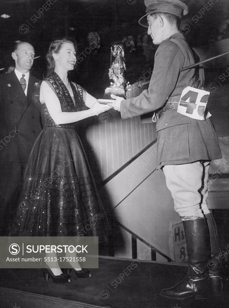 So The Cup Changes Hands - Princess Elizabeth, in a dark spiral-embroided evening dress presents the George V Gold Challenge Cup to Capt. K. Barry of the Eire Army, at the International Horse Show, at the White city, London last night. Captain Barry on his chestnut mare Ballyneety, had the only clear round in the finals. Lt. Col. Harry Llewellyn, Winner in 1948 and last year, came to grief on a white wicket gate which proved the "graveyard" of many hopes during the evening. Lt. Col. Harry Llewellyn was riding Foxhunter. July 26, 1951. (Photo by Paul Popper).