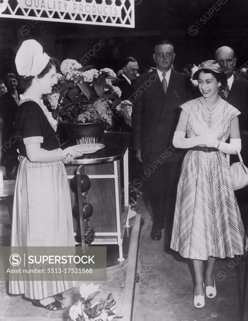 Queen At the Food Fair- Queen Elizabeth, in a cool summer dress and long white gloves, passes a girl in Dutch costume holding a plate of 'tastes' of Dutch cheese, during a private visit to the British Food Fair, Opening at Olympic to-day. July 5, 1952.