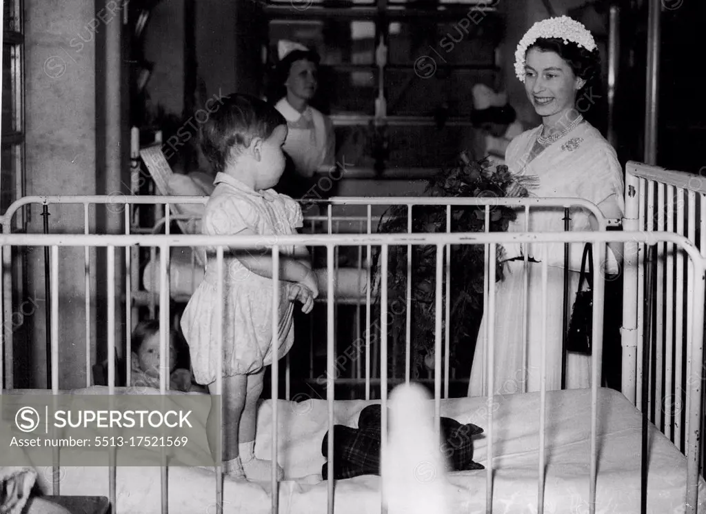 Queen Meets Hospital Baby - London: Wearing a Summer dress of Pleated white chiffon, and a tiny East to West cap of white ***** the Queen stops to talk to Reginald Parker, aged eighteen months (from Rochester, Kent) while visiting the Great Ormond Street (London) hospital for Children. July 23, 1952.