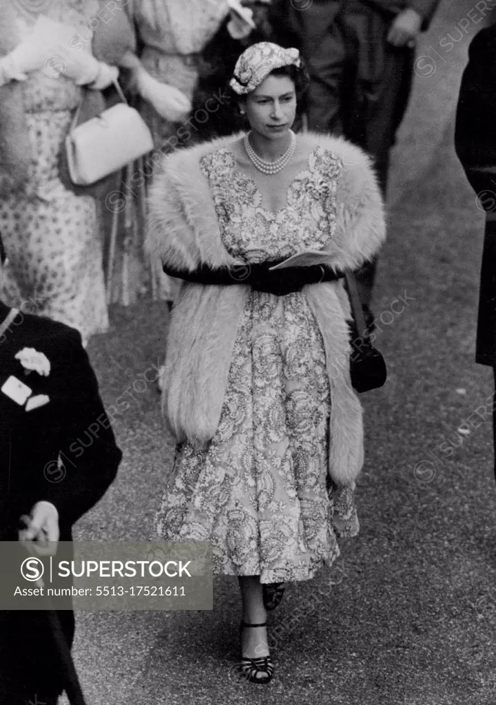 The Queen's Ascot Fashion For Ladies Day -- H.M. The Queen seen walking to the Paddock at Ascot this afternoon. For Ladles Day Her Majesty was charmingly dressed in a filmy white lace dress embroidered overall In fins navy blue braid. Her tiny head hugging forward tilting hat, was to match and The Queen had a fur round her shoulders as protection against the cool breezes. Two outstanding features of her ensemble were the attractive scalloped V neckline of her dress and the extra long handle to her handbag. Today was Ladies Day at Ascot - the third day of the Meeting and several members of the Royal Family, including Her Majesty the Queen were again among the spectators at the Course. June 17, 1954. (Photo by Fox Photos).