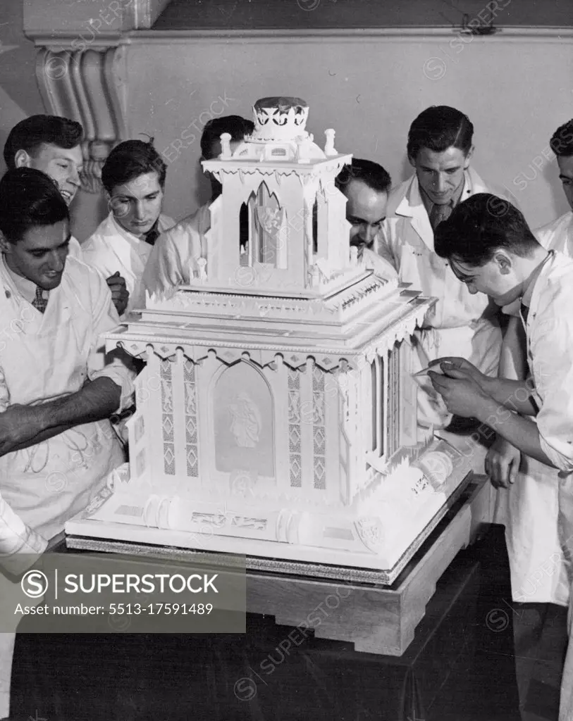 Royal Christening Cake Weighs Over A Hundredweight One of the students at the Borough Polytechnic at work on the cake watched by fellow-students. The front panel depicts a motherhood scene. A christening cake weighing over a hundred weight will by presented to Princess Elizabeth by the National Association of Master Bakers. The cake has been made by students of the National Bakery school, London, who have had only 15 months training. It has one tier, is 36 inches high, and follows traditional liens. Square in design, it is surmounted by a canopy of sugar supporting the Royal Crown. December 09, 1948. 