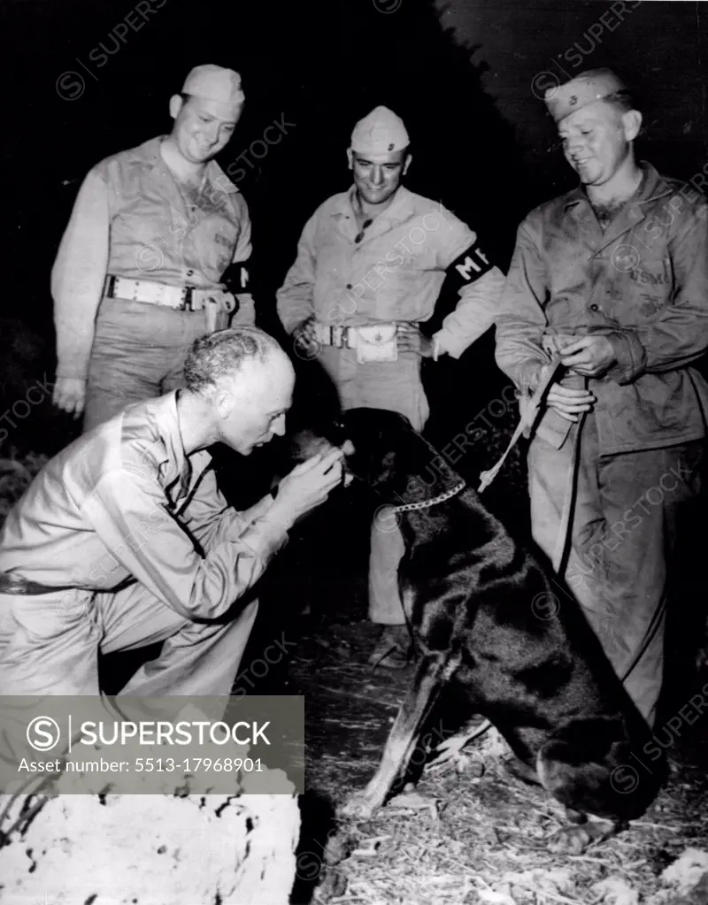 Ernie Pyle On New Beat -- Ernie Pyle (left), war correspondent who recently left the battlefields of Europe to cover the Pacific theater of war, gets acquainted with two types of Devil dogs, "Somewhere in the Pacific". It was the first time Pyle, celebrated for his stories on enlisted men of the battlefields, met a marine War Dog. The dog is "Jeep", a scout and security patrol Doberman Pinscher. They met while "Jeep" was on a regular guard watch, near the command post of Major General Graves B. Erskine, Commanding General of the Third Marine Division. February 9, 1945. (Photo by Official U.S.Marine Corps Photo).