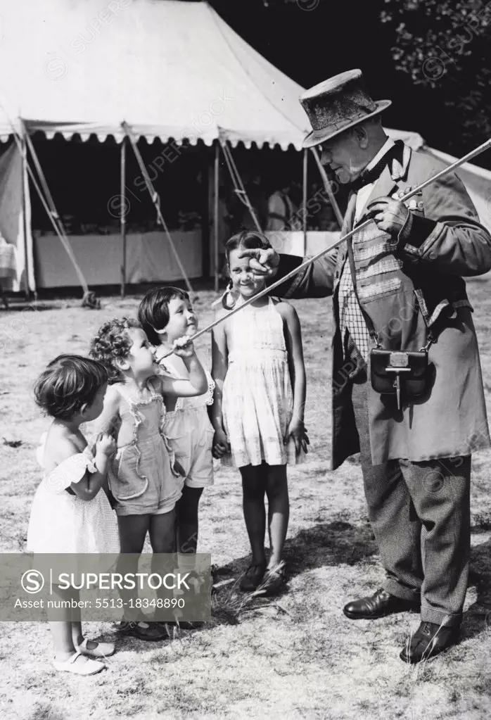 Children Meet "Captain Hornblower" -- Harry Love, the coaching horn champion seen teaching 4 youngsters how to blow the coach horn during the recent Horse show at Teddington. The youngsters attempting the "Long Blow" are (Left to Right : Carol Bowley (2) from Hove and three sisters all from Hampton, Barbara (3), Mary (4) and Sally Plumbley (7).One of the most popular items during the 1955 Twickenham Fair was the Horse Show and Gymkhana which took place recently at The Pleasure Grounds, Teddington (Mddx), A great favourite with young spectators at this show was Harry Love of Kingston the Professional Coaching and Ring Guard who is often in attendance at such events. Harry has been a horn-blower for the past 60 years and is a champion at the art of blowing the coaching horn. September 05, 1955. (Photo by Fox Photos).