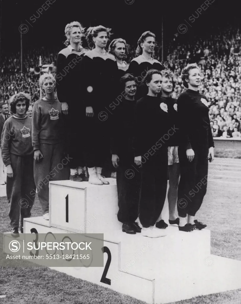 Olympic Games - Blankers-Koen wins Fourth Olympic Medal - and Relay for Holland : Mrs. Fanny Blankers-Koen and members of the winning Dutch team, together with runners-up stand to attention on the Victory Rostrum at Wembley Stadium as the National Anthems are played in tribute to their triumph in the women's 400 metres relay. By winning the relay for Holland, Mrs. Blankers-Koen achieved her fourth victory in the 1948 Olympics. Second in the race were the Australians, with the Canadian women third. August 06, 1948. (Photo by Olympic Photo Association).