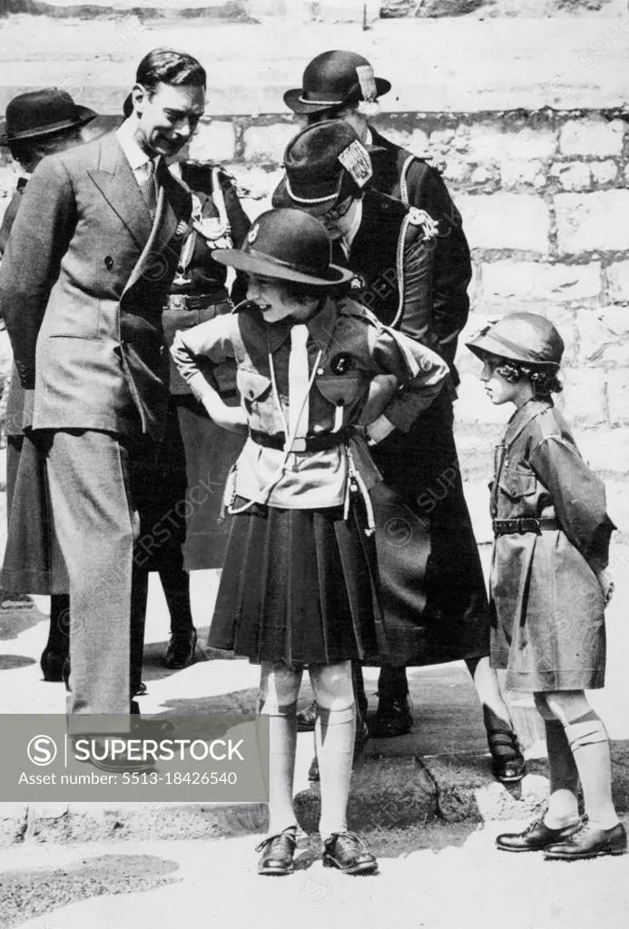 Girl Guides Inspection At Windsor A charming incident during the March Past of the Girl Guides. Out photograph shows Princess Elizabeth having the belt of her uniform adjusted. His Majesty King George VI is looking on. Princess Margaret is seen on the right in the Brownie uniform. This is the first time the Princesses have attended a function in their Girl Guides uniform. July 11, 1938.