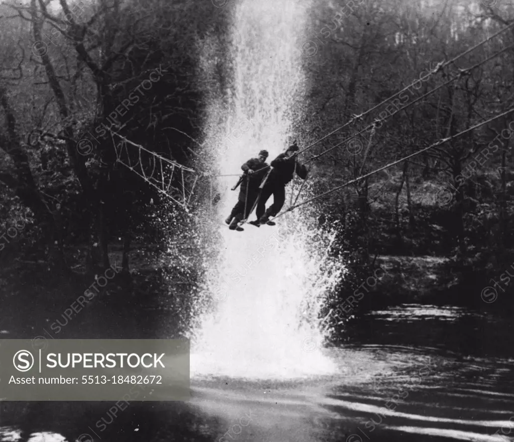 Newspaper Correspondents See Commandos In Training: The death ride.. Commandos cross a river under enemy fire, by means of a toggle bridge. Newspaper correspondents have witnessed a Commando training demonstration in the Scottish Command. They saw Commandos destroy an "enemy" strong point, the way in which they use ropes for climbing and hauling themselves up the cliff face, and crossing a river under fire. January 13, 1943. (Photo by Fox Photos).