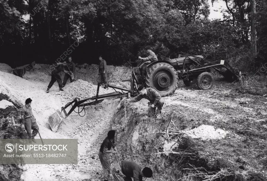 The British Army goes Back to Digging -- Men and machines hard at word digging-in during the first stage of the exercise. Pinks, shovels and mechanical "diggers" formed a large part of the equipment for officers and men of the 43 Infantry Division taking part in an "atomic warfare" exercises on Salisbury Plain. During the exercise an "atomic explosion" will be simulated while the Division takes shelter in its newly dug trenches and dug-outs. September 14, 1955. (Photo by Sport & General Press Agency, Limited).