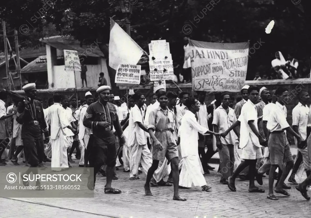 Postal Strike in Bombay -- Postal employees on strike, kept in line and shepherded by policemen, who are seen carrying umbrellas, marching through a street in Bombay with placards proclaiming their demands, on July 15.Three hundred strikes arising out of industrial disputes have taken place in Bombay this year. Ten strikes are at present in progress, including the stoppage of postal and telegraph workers, and two more are pending.The postal workers struck on July 11 seeking an increase in wages of about 20%, and the strike is still in progress. July 24, 1946. (Photo by Associated Press Photo).