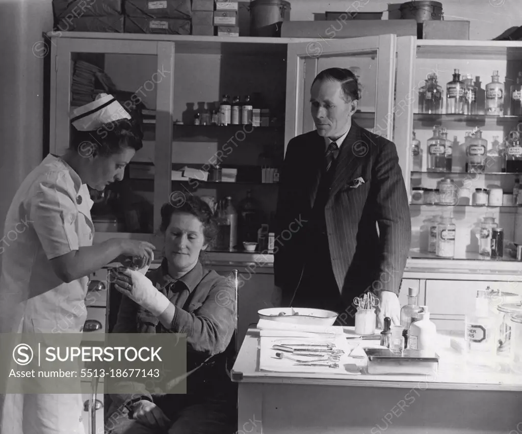 New Career In Industry: His Job Is "Labour Relations" -- He sees that the first aid service is working well; between twenty and thirty minor injuries are dealt with each. Here Nurse Williams bandages the hand of Mrs. Kathleen Varley, who has injured her fingers while loading casks. November 28, 1947. (Photo by Pictorial Press).