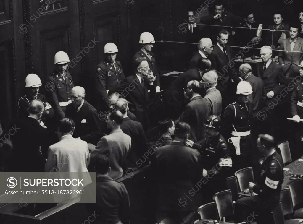 Nuremberg Defendants Talk it Over -- Some of the defendants in the Nuremberg trial discussing some of the verdicts that had already been delivered when a short recess was ordered this morning, at left, Ribbentrop (left of Goering) Von Papen (talking to Ribbentrop) and Hess, on right of Goering, are easily recognized. In centre (with glasses) is Seyss Inquart and facing him (slightly bald headed) is Frank: next to him on right is Frick and to his right is Funk, with Dr Schact in the extreme right hand corner. In corner opposite Schacht is Fritsche and next to him (white haired) is Von Neurath. October 9, 1946. (Photo by Associated Press Photo).