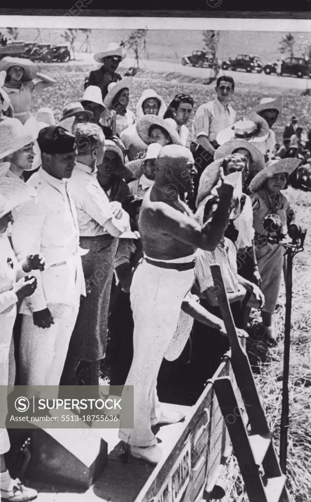 Mussolini Strips To The Waist - Helps In Wheat Harvest -- A striking picture of Mussolini, stripped to the waist, making his bitter speech against his critics.Stripped to the waist, and standing on a threshing machine in the wheat fields of the Pontine Marshes, Mussolini on Monday made his bitterest, fieroest attack against democracies since the days of Sanctions. He spoke at Aprilia, a village that has been built in the reclaimed marshes. He made scathing replies to reporters that Italy  is short of Grain. July 6, 1938. (Photo by Keystone).