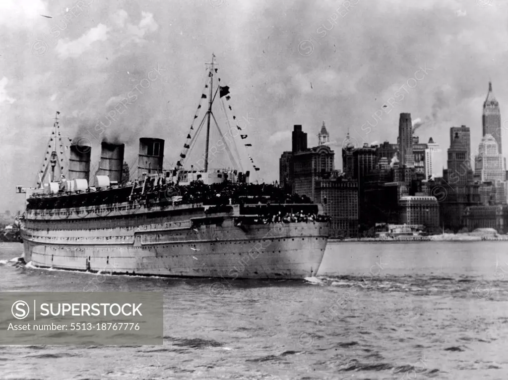 Queen Mary Brings Home American Soldiers -- The towering skyline of lower New York City is a welcome sight to 14,526 American fighting men returning from Europe. They crowd the decks of the British transport Queen Mary, as the former trans-Atlantic luxury liner moves up New York Bay June 20,1945. The largest con­tingent of servicemen ever to arrive in tie port on a single ship, most of them were destined for redeploy­ment to the Pacific. The voyage was the Queen Mary's first westward trip free of menace since the beginning of the war. July 27, 1945. (Photo by U.S. Office of War Information Picture).