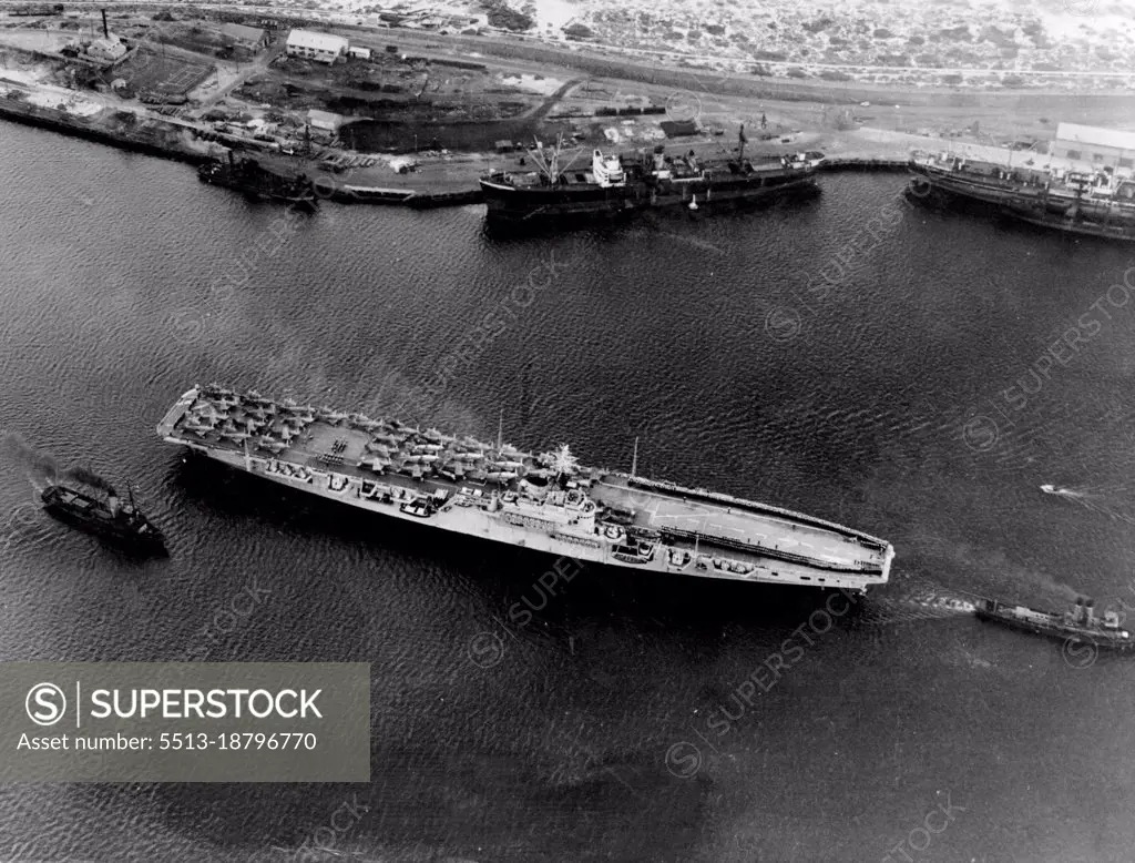 New Carrier reaches Australia. Australia's new aircraft carrier, HMAS Sydney photographed moving into Fremantle Harbor today on her arrival from England. Flights of aircraft can be seen on the carrier's deck, and the thin, dark lines forward are formed by her complement at stations for harbor entry. May 13, 1949. 