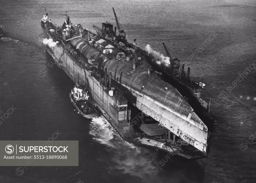 Great Clyde Towing Feat -- Towed by eight tugs, a 42,000-ton floating dock with the former German battle cruiser "Derfflinger"- recently salvaged from Scape Flow - aboard, was yesterday taken up the Clyde to Faslane to the breaking-up yards. The huge German ship, still in its upside-down position, was larger than the dock, and overlapped at each end.This picture taken from a specially chartered aircraft shows the dock with the "Derfflinger" on board being towed up the Clyde. November 16, 1946. (Photo by United Kingdom Information Office).