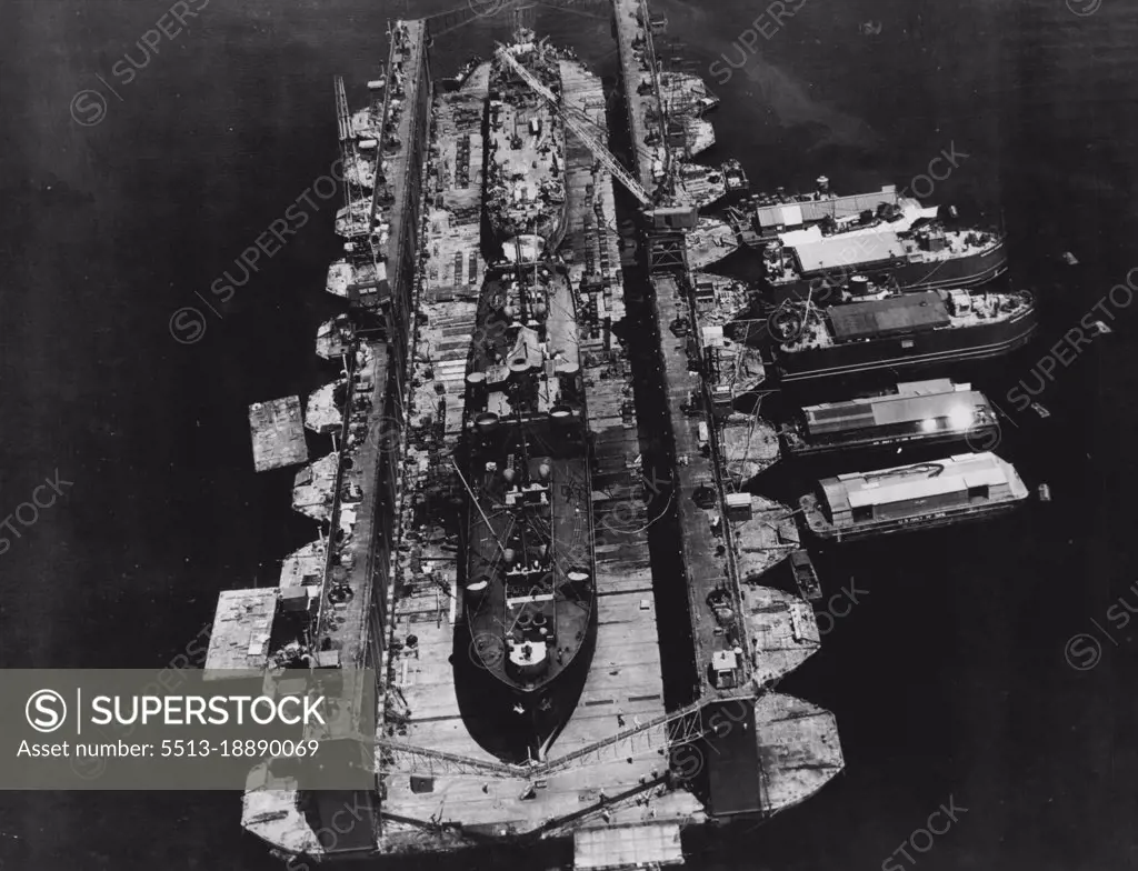 Floating Drydocks Serve U.S. Fleet In Pacific -- Two battle-damaged U.S. Navy ships receive simultaneous attention in this huge ten-section floating drydock. Floating machine shops secured alongside provide additional facilities. The huge drydocks, towed in sections to Pacific combat areas, save damaged ships the long trip back to the U.S. for repairs. July 18, 1945. (Photo by U.S. Office of War Information Picture).