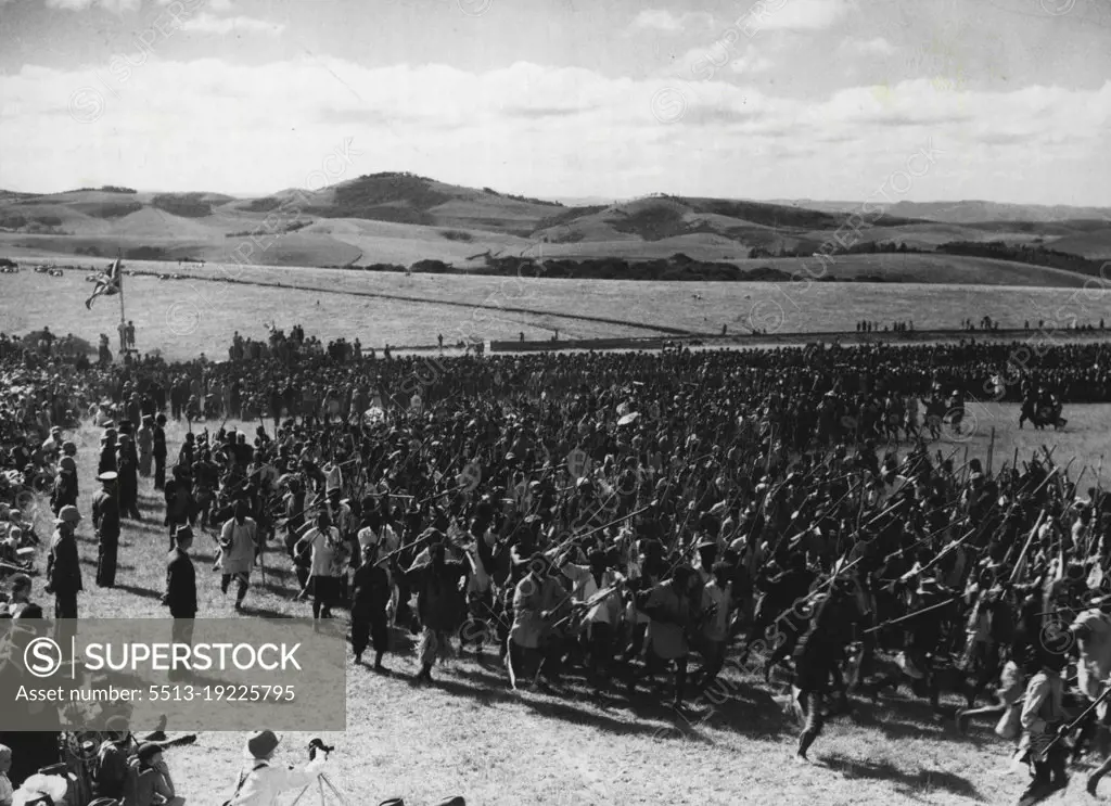 The Royal Family Witness Zulu Dance -- The Zulu dance for the Royal Family in progress at Eshowe.A Royal Dance was arranged at Eshowe on March 19th for the occasion of the visit of the Royal Family. Zulu warriors, with Shields and assegais staged a revival of a ceremony belonging to an order of African society now obsolete. At the end of the dance, the Zulus, with tossing plumes and brandished assegais and knobkerries, surged up to the royal stand and almost shock the earth with the stamp of naked feet. March 24, 1947. (Photo by Topical Press).